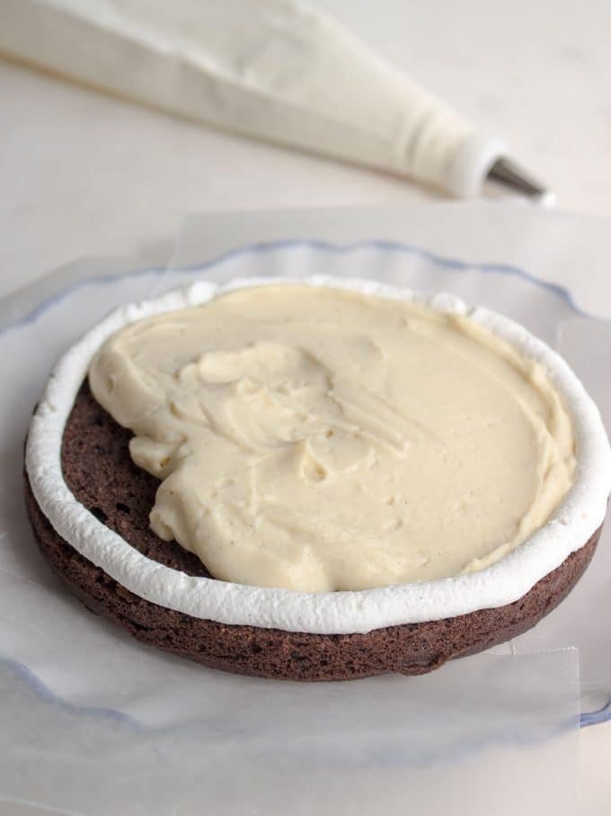 A primeira camada de um bolo de camada de chocolate com enchimento de pudim de baunilha e enchimento de baunilha.