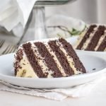 Uma fatia de bolo de camada de chocolate baixo em carboidratos, preenchido com pudim de baunilha, em um prato.